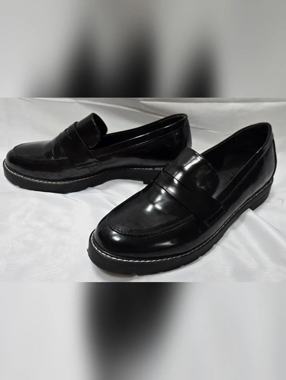 JustFab Black glossy penny loafers with chunky lug soles and contrast stitching.